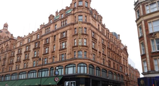 A six-storey biulding, bearing the name 'Harrods,' is seen from a street corner.