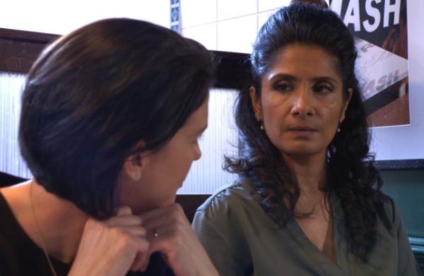 Eve and Suki looking at each other in a booth in Beale's Eels in EastEnders